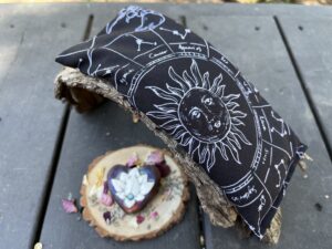 black rectangular eye pillow with celestial design in natural setting